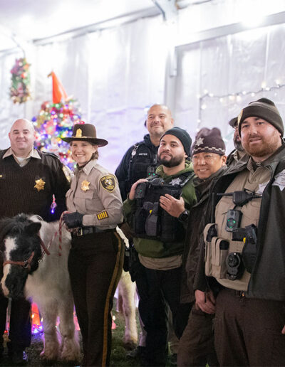 A group photo of several officers. One of them holds the reigns to a miniature pony.
