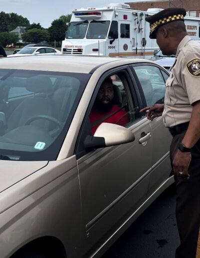 Undersheriff Marlon Parks greets a Richton Park Resident who waiting to get his car serviced under Sheriffs Lightsaver Program