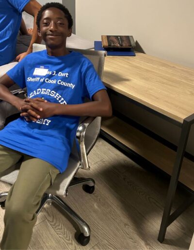 A boy sits in a swivel chair, smiling at the camera