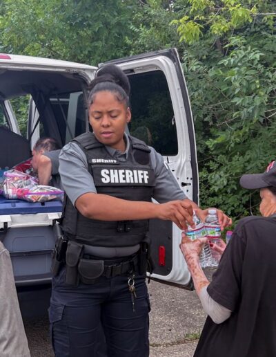 OFFICER SHAVONIA BROWN HANDS OUT WATER TO INDIVIDUALS AT HOMELESS ENCAMPMENT ON 31ST CICERO