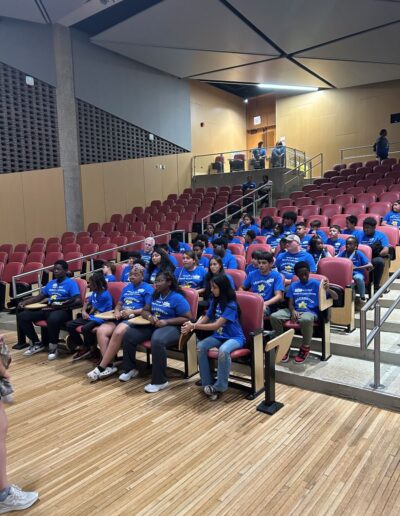 Several students sit in an auditorium, presumably listening to a presenter