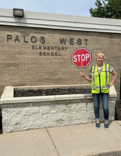 Crossing guard Gale poses with a stop sign outside of Palos West Elementary School